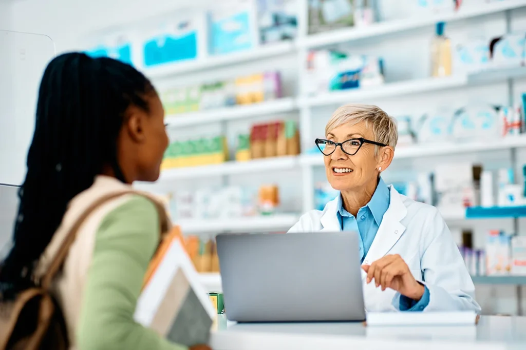 happy senior pharmacist talking to her female cust